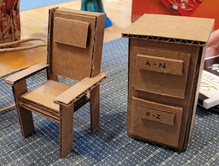 Small cardboard models of a chair and a filing cabinet.