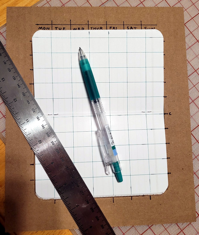 Picture of a notebook in the template with a ruler and pen and completed grid.